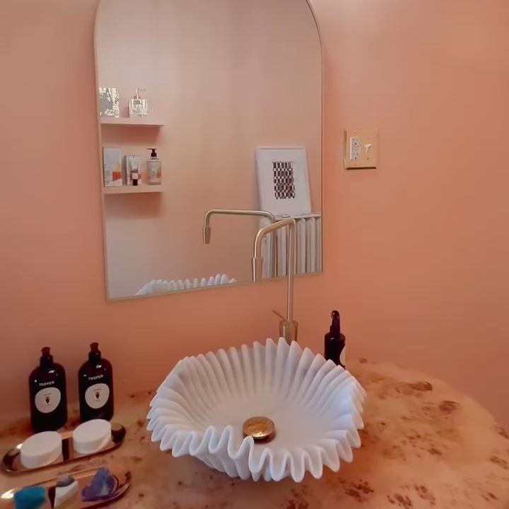 Ripple marble sink installed in luxury bathroom with gold faucet